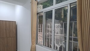 A room with a large window, a wooden wardrobe, and a curtain. - Hotel East Inn (Gangtok)