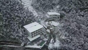 A snow-covered building with a flat roof, surrounded by dense forest. - Rest Valley (Deqing)