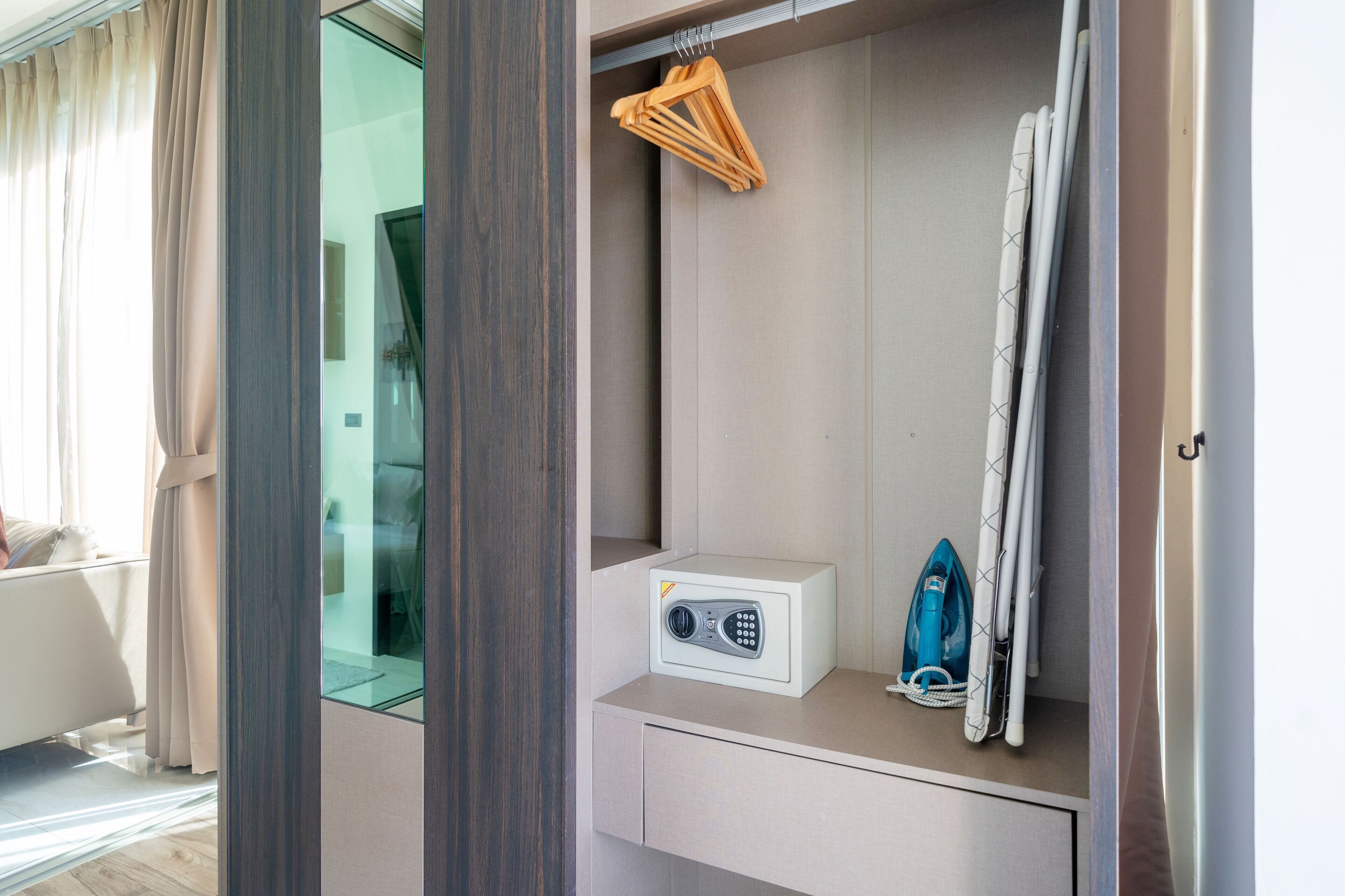 Habitación de hotel con microondas integrado, una plancha pequeña y un perchero.