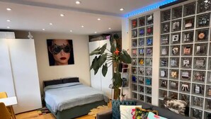 Ein modernes Schlafzimmer mit einem Bett, einer Couch, einem Schreibtisch und einer Wand mit Dekoration.