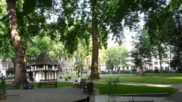 Ein Park mit Bänken, einem Pavillon und einer Rasenfläche.