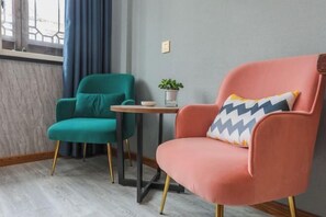 Relax in this inviting room with a teal armchair, a pink armchair, and a small table.