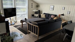 A modern bedroom with a bed, a desk, a chair, a TV, and a balcony with a view.