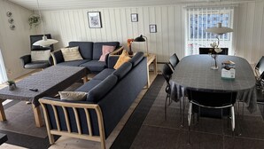 Una sala de estar moderna con un sofá modular, una mesa de comedor y un amplio ventanal.