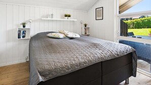 A bedroom with a bed, white walls, a window, and a view of the outside.