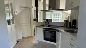 A modern kitchen with white cabinetry, a built-in oven, and a coffee maker.