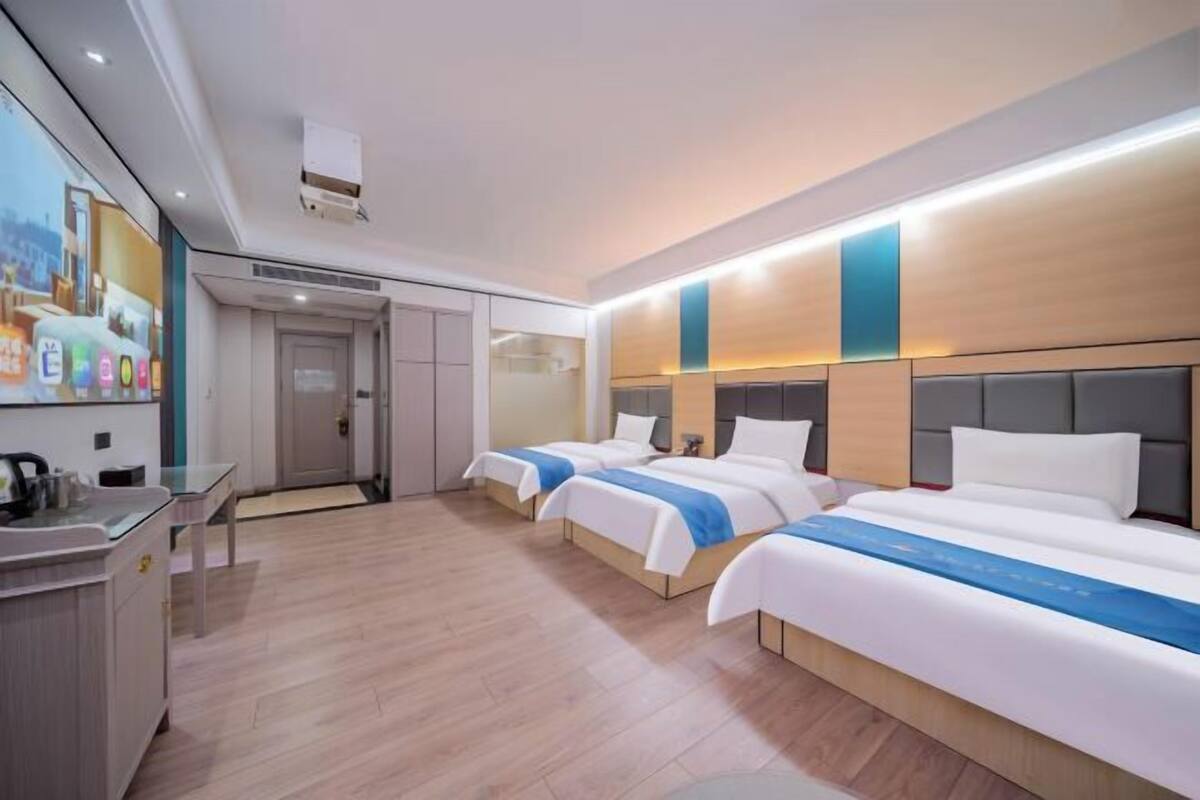 Ein Hotelzimmer mit zwei Betten, einem Schreibtisch mit Waschbecken und einem großen Fenster.