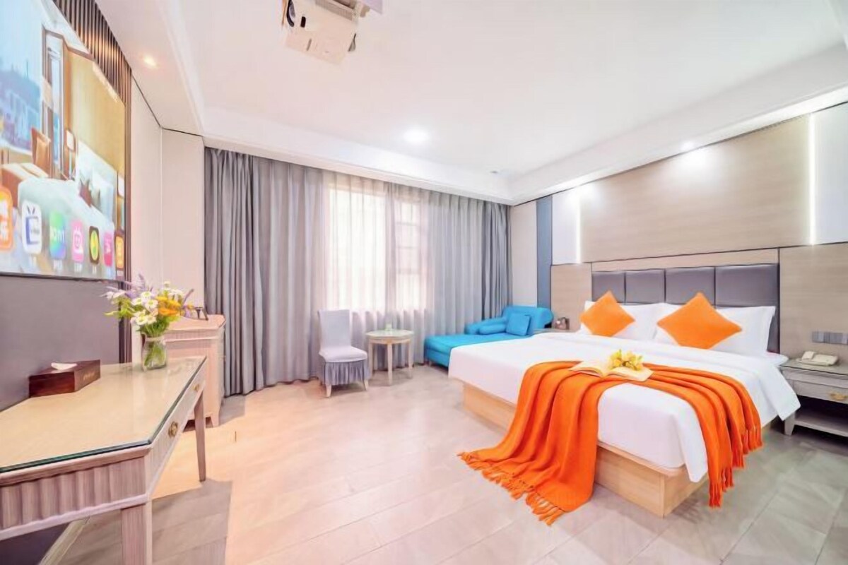Una habitación de hotel con una cama, un escritorio, una silla, una mesita y una ventana con cortinas.