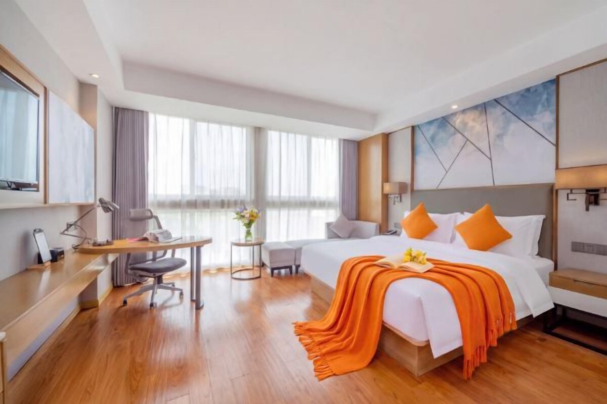 Habitación de hotel con una cama grande, un escritorio, una silla y una mesita.