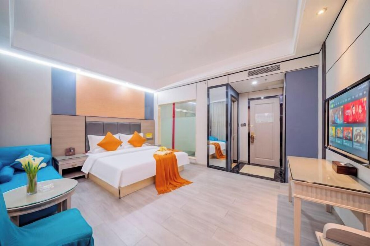 Una habitación de hotel moderna con cama, escritorio, televisión y zona de estar.