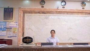 Een receptiebalie met een marmeren wand, een klok en een bord met Chinese karakters.