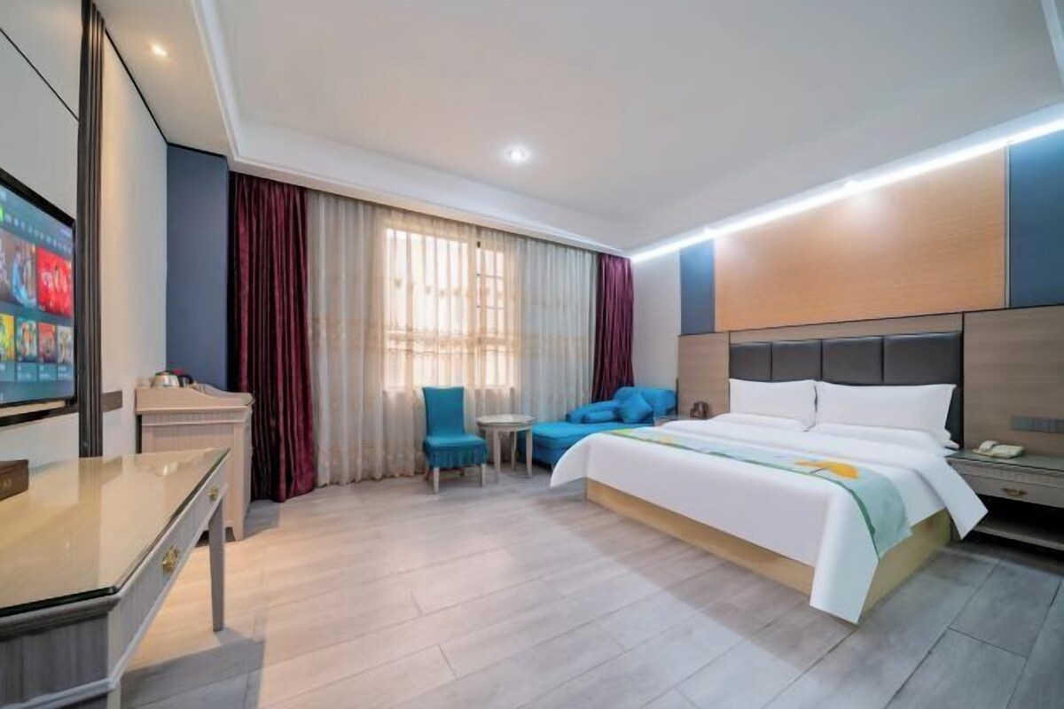 Ein Hotelzimmer mit Bett, Schreibtisch, Fernseher, Stuhl und kleinem Tisch.