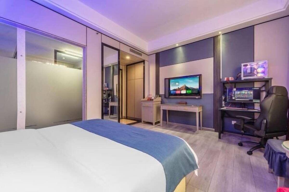 Ein Hotelzimmer mit einem Bett, einem Schreibtisch mit Computer, einem Fernseher und einem Sessel.