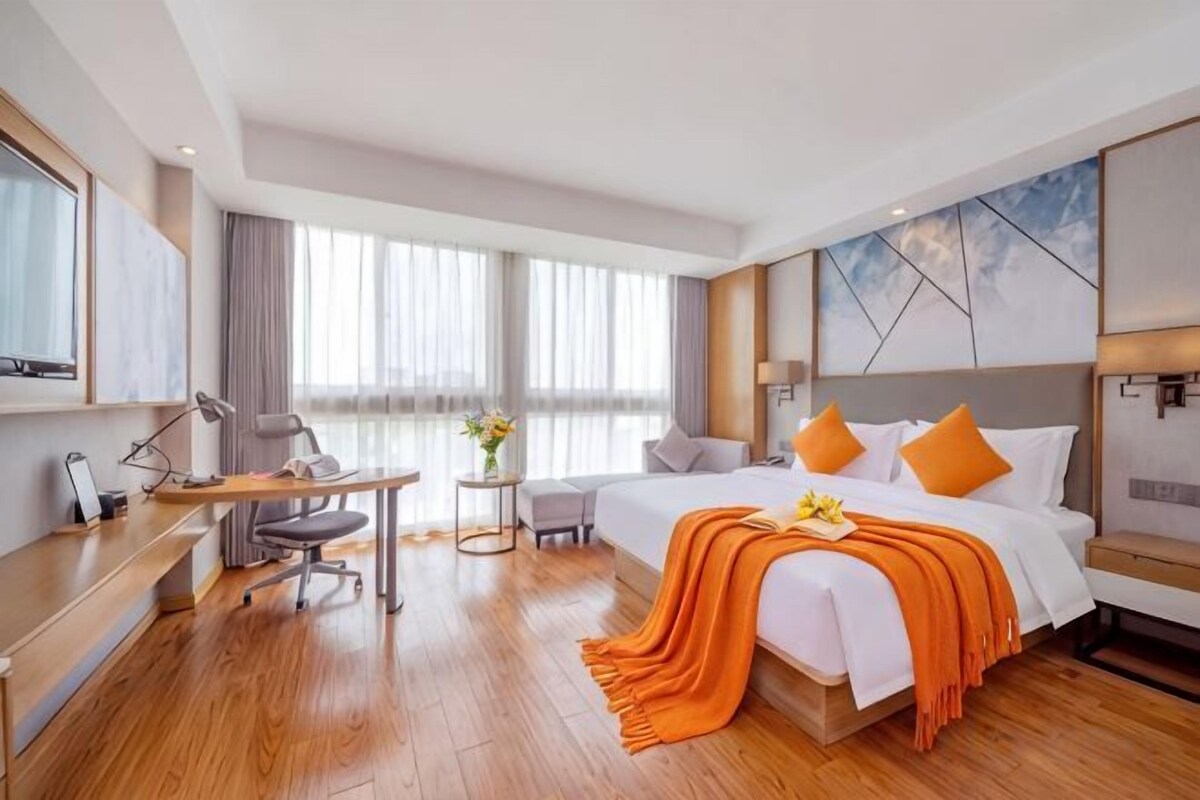 Une chambre d’hôtel équipée d’un lit, d’un bureau, d’une chaise et offrant une vue sur l’extérieur.