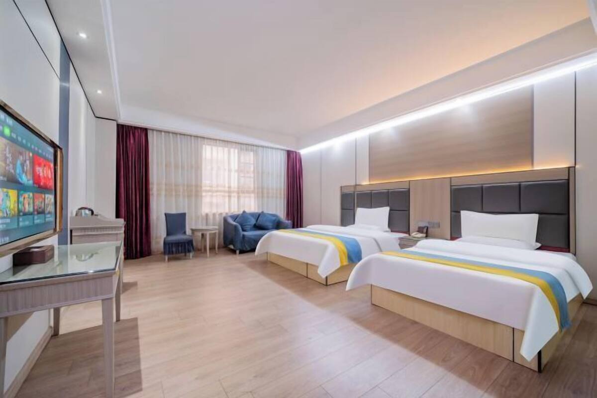 Ein Hotelzimmer mit zwei Betten, einem Fernseher, einem Schreibtisch und einem Stuhl.