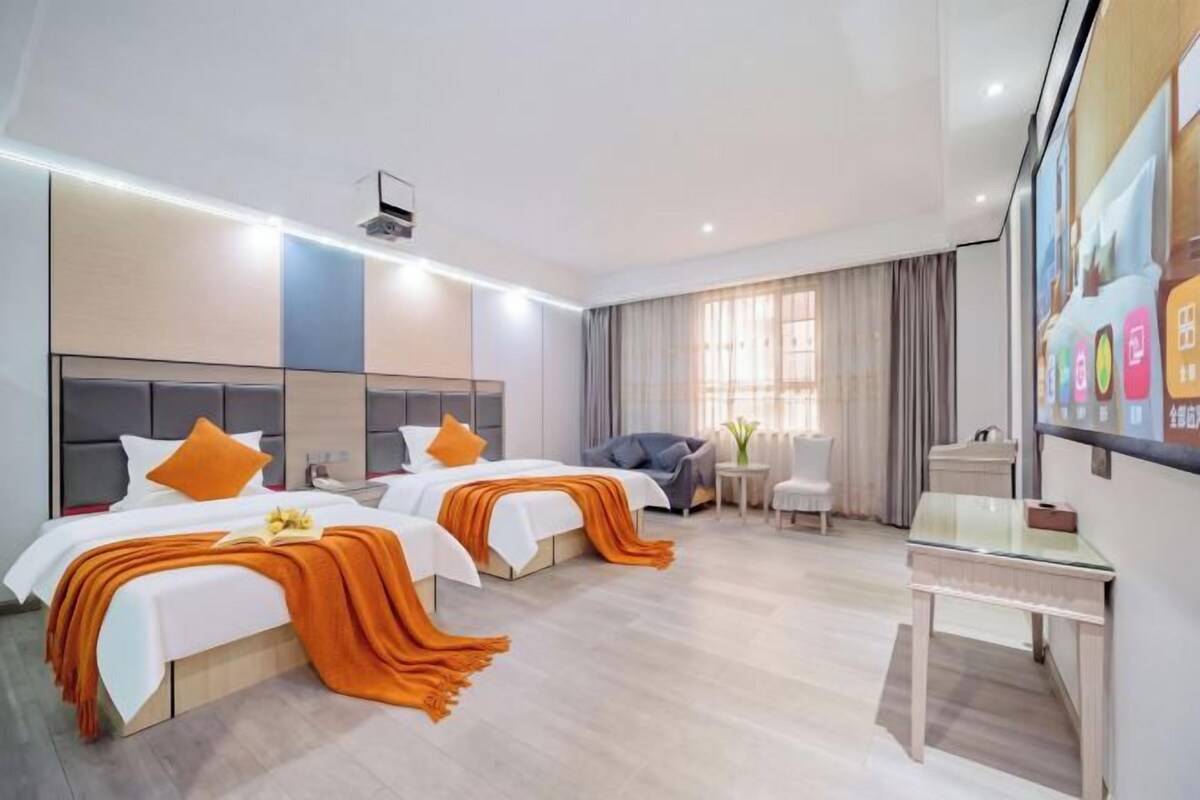 Habitación de hotel con dos camas, un escritorio y una silla.