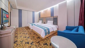 Een hotelkamer met twee bedden, een bureau, een blauwe bank en een kamerbreed tapijt met dessin.