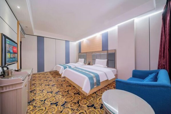 Une chambre d’hôtel avec deux lits, un bureau, un canapé bleu et une moquette à motifs.