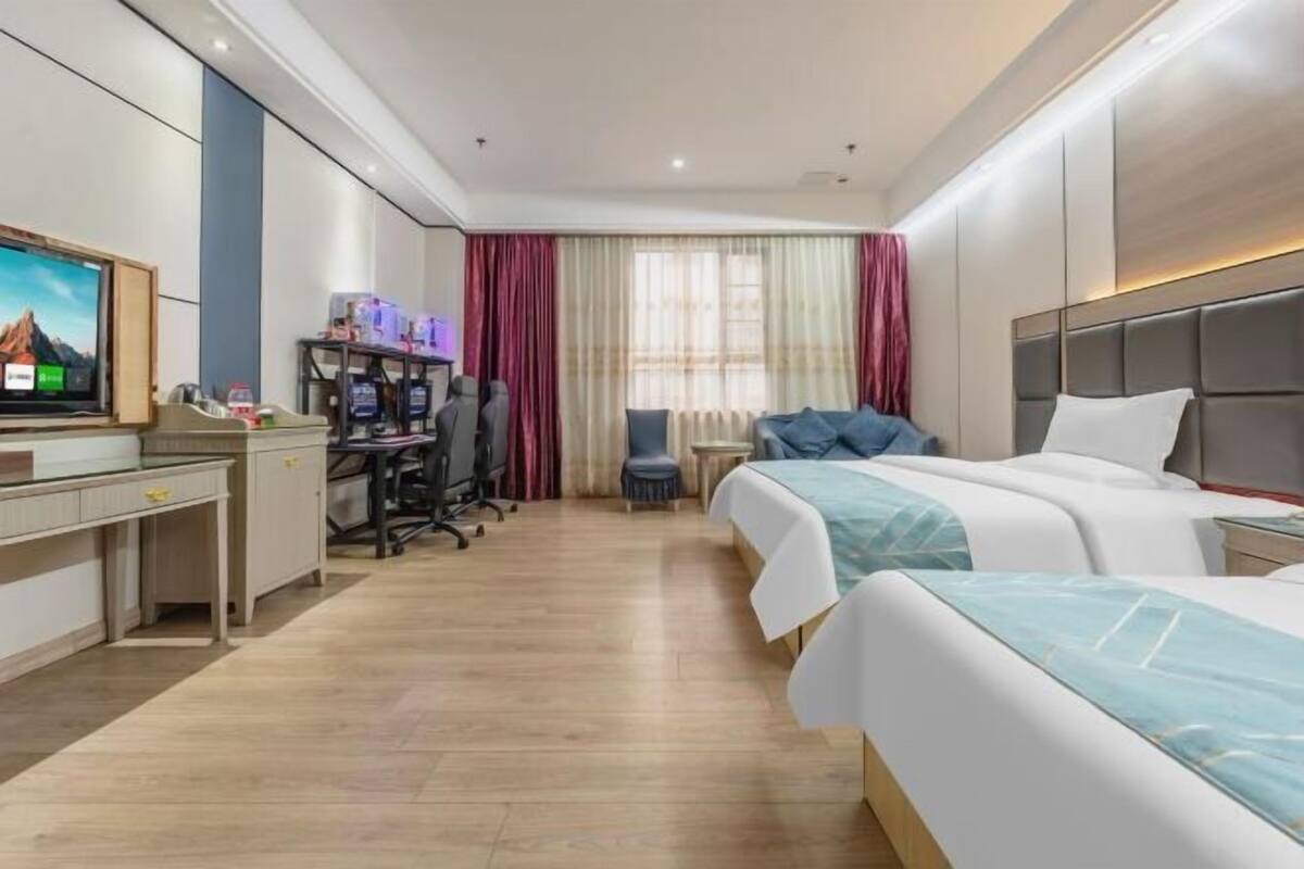Ein Hotelzimmer mit einem Bett, einem Schreibtisch, einem Sessel, einem Fernseher und einem kleinen Tisch.