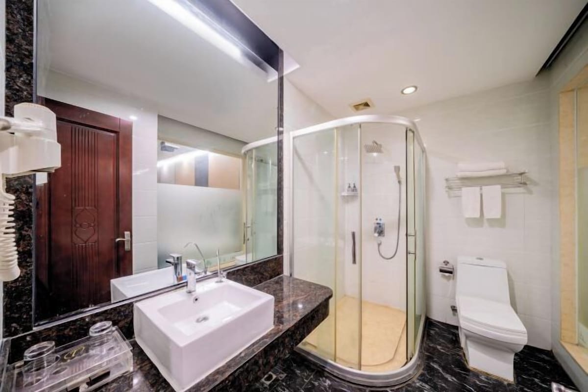 Une salle de bain moderne avec une douche à parois de verre, un lavabo blanc et des toilettes.
