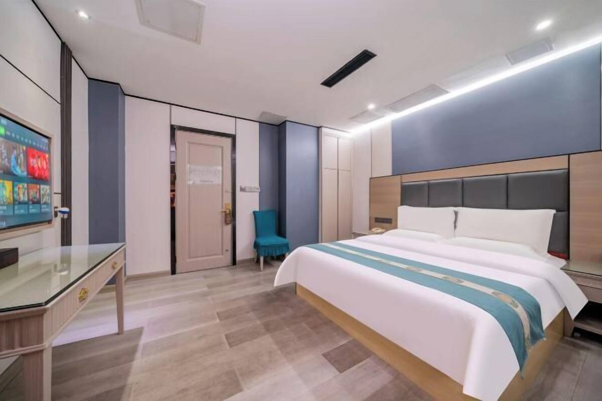 Ein modernes Hotelzimmer mit einem Bett, einem Schreibtisch, einem Stuhl und einem Fernseher.