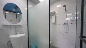 A bathroom with a white sink, a glass shower enclosure, and a circular mirror. - Jinyuan Express Hotel (Beijing)