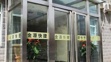 A building entrance with glass doors and metal frames, featuring signs with Chinese characters.