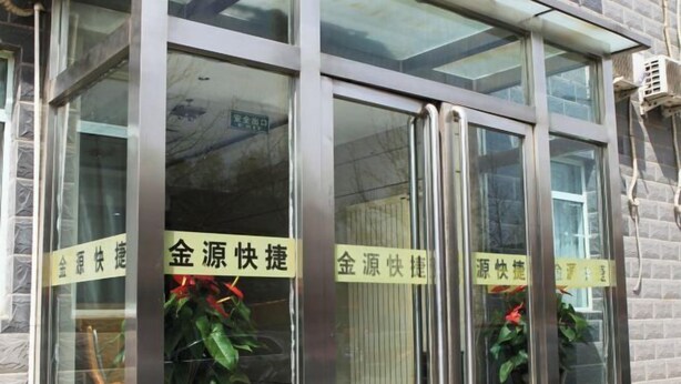 A building entrance with glass doors and metal frames, featuring signs in a foreign language. - Jinyuan Express Hotel (Beijing)