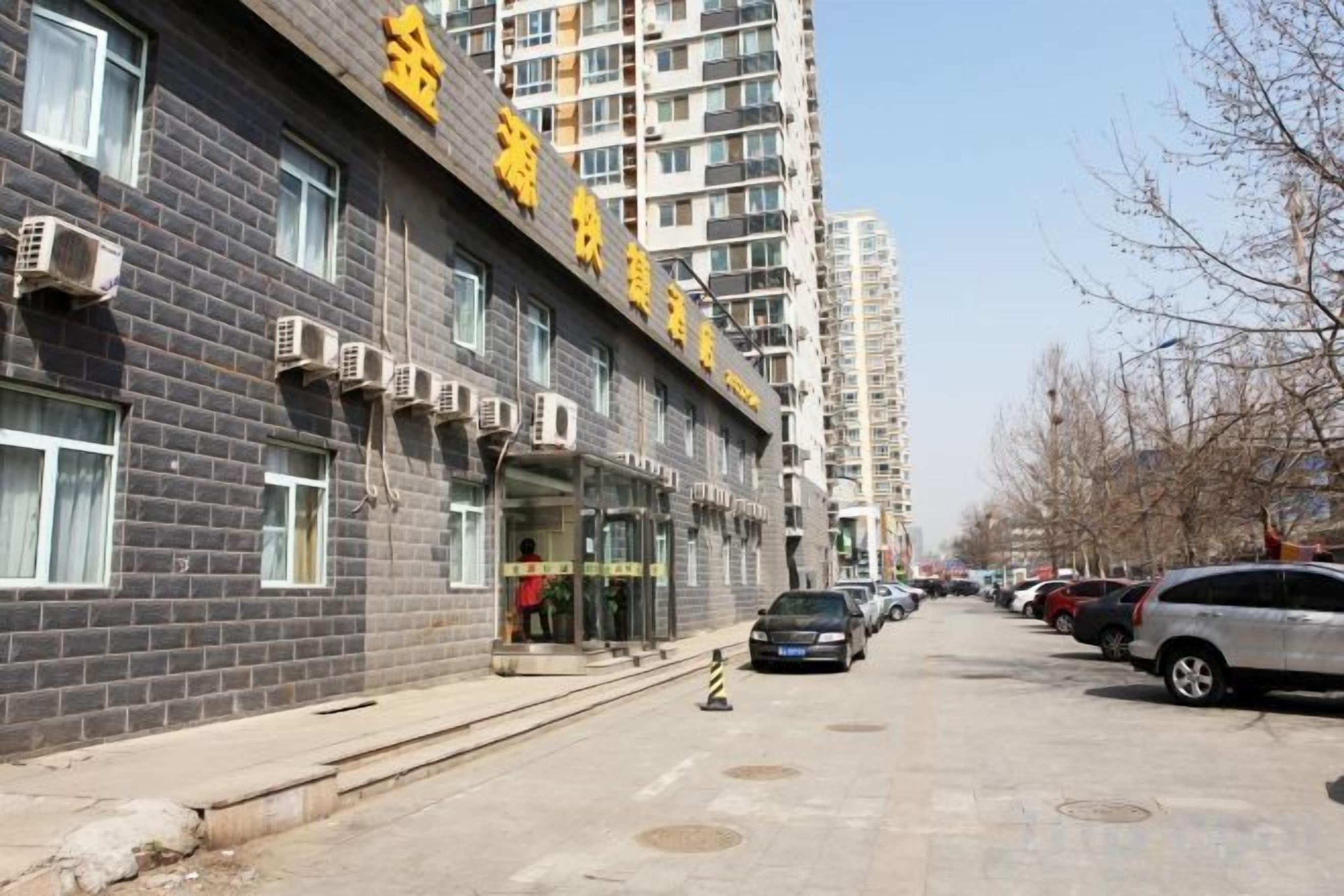 A multi-story building with a visible entrance and parked cars along the street.