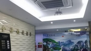 A hotel reception area with a modern design, including a digital display board, a large mural of a mountainous landscape, and a ceiling with a ventilation system. - Jinyuan Express Hotel (Beijing)