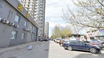 A multi-story building with a sign indicating it is a hotel. There are parked cars along the street, and a tree with bare branches is visible.