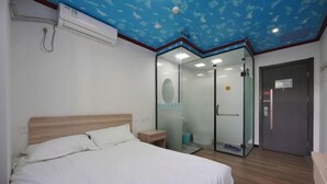 A bedroom with a bed, a glass-enclosed shower, and a door to the bathroom. - Jinyuan Express Hotel (Beijing)