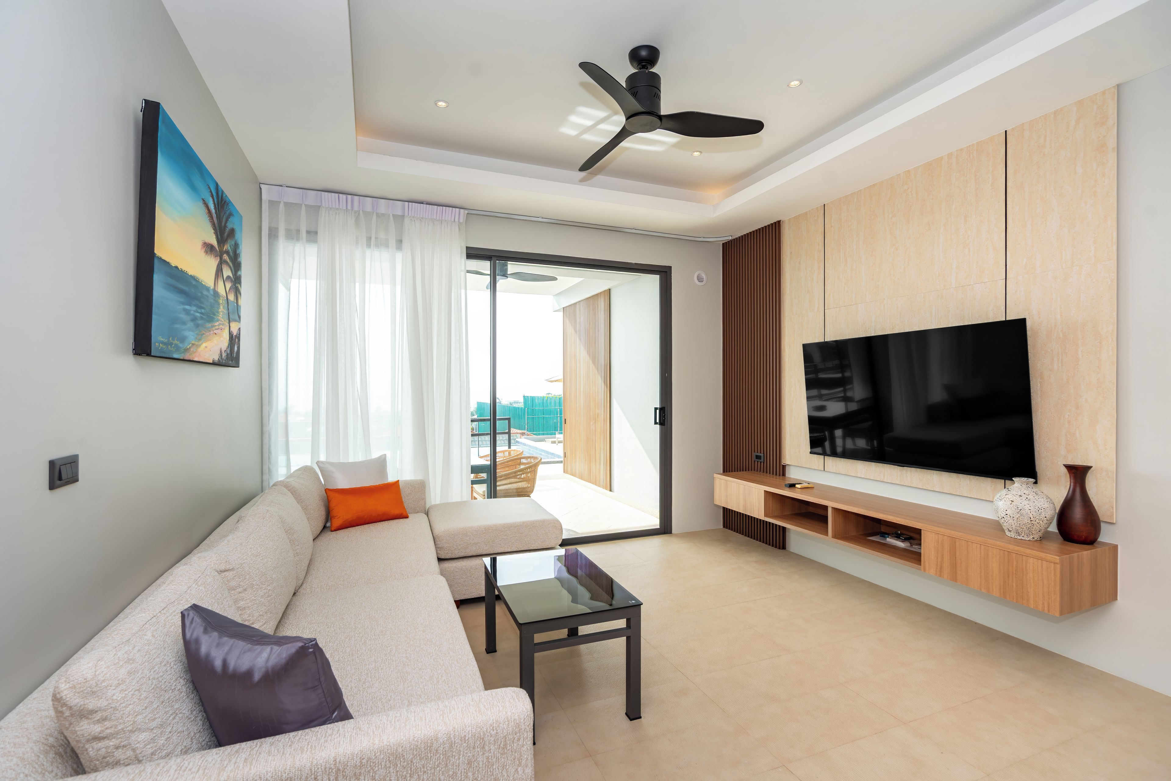 A modern living room with a sofa, a coffee table, a TV, and a ceiling fan.