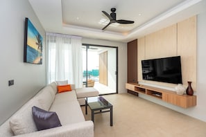 A modern living room with a sofa, a coffee table, a TV, and a ceiling fan. - Hillside Seaview Residence (Karon)