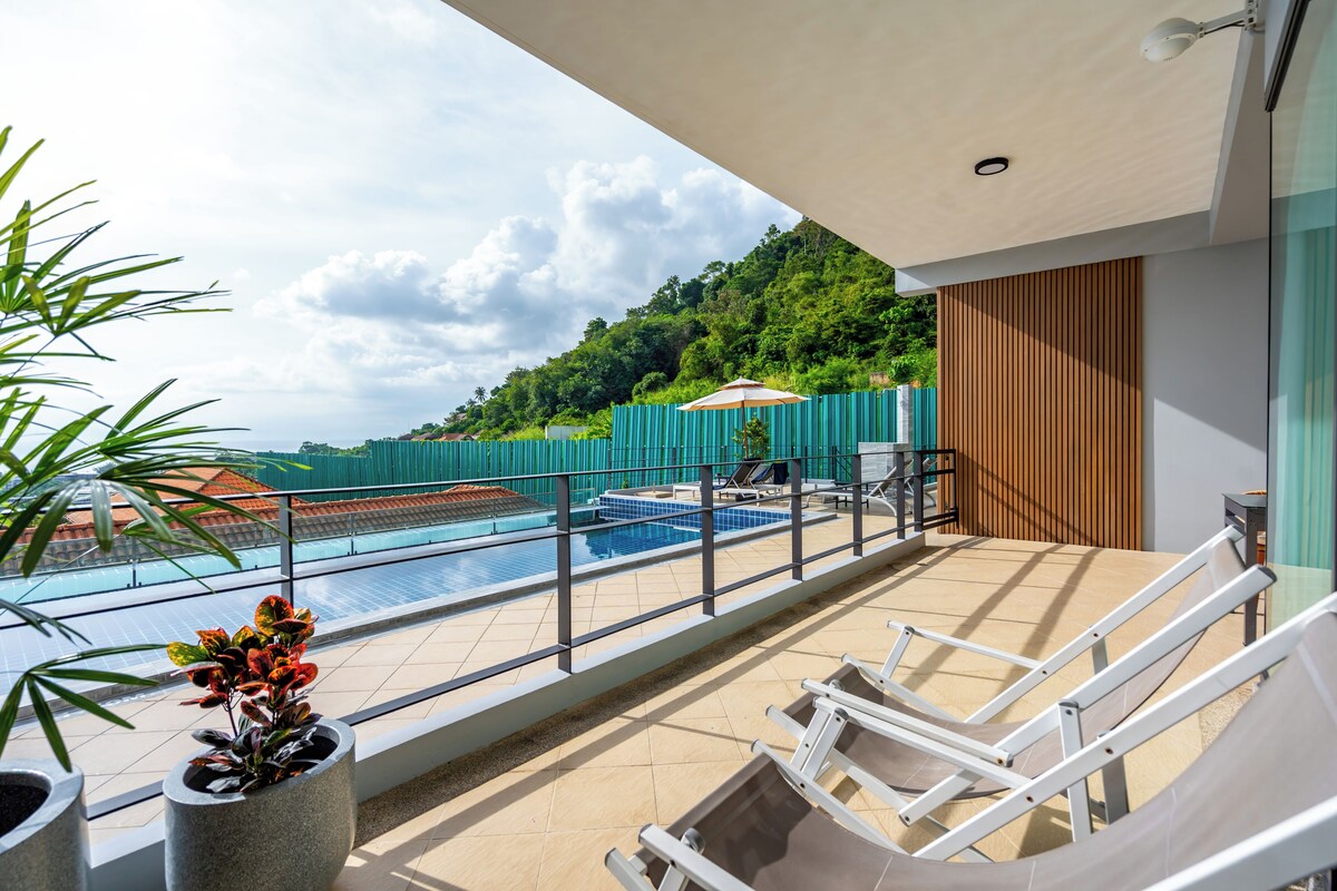 Un balcon avec une piscine, des chaises longues et une vue sur une colline.