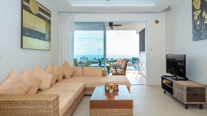 A living room with a sofa, coffee table, and TV stand. - Hillside Seaview Residence (Karon)
