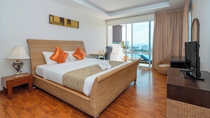 A hotel room with a large bed, a TV, a desk, and a view of the city. - Hillside Seaview Residence (Karon)