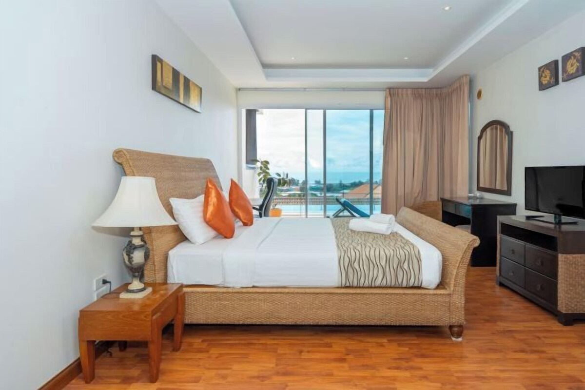 A hotel room with a bed, a desk, a television, and a view of the city.