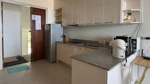 A modern kitchen with white cabinets, a stainless steel refrigerator, a coffee machine, and a sink. - Hillside Seaview Residence (Karon)