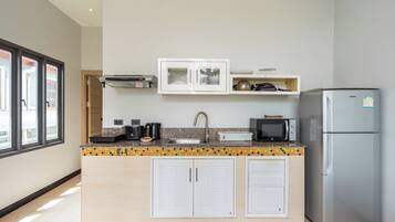 Een moderne keuken met witte kasten, een roestvrijstalen koelkast, een magnetron en een koffiezetapparaat.