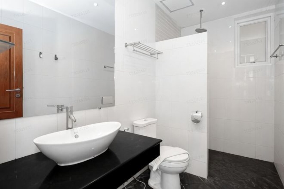 Een moderne badkamer met een witte wastafel, een zwart aanrecht, een wit toilet en een douchegedeelte.