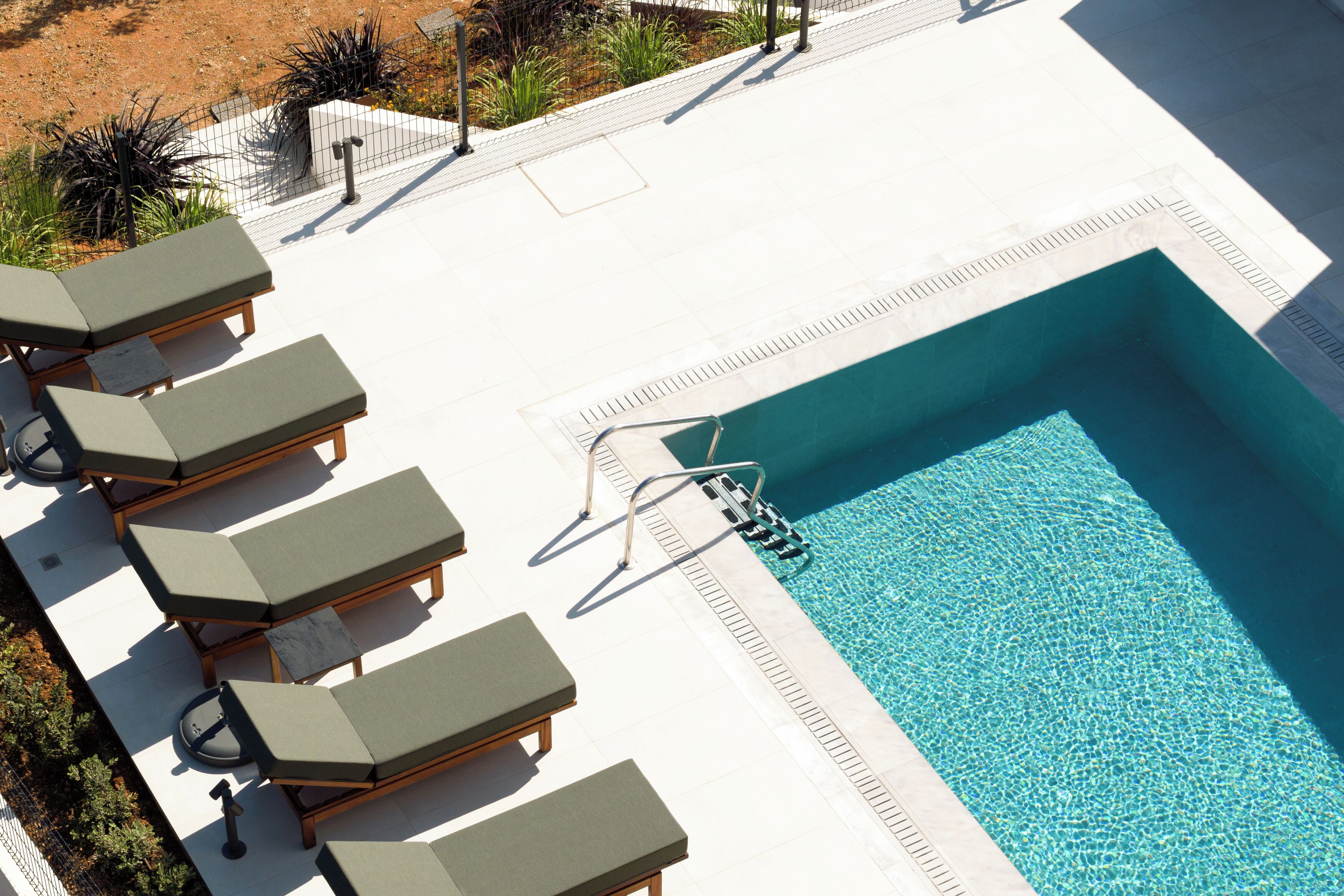 A pool area with lounge chairs and a clear blue pool.