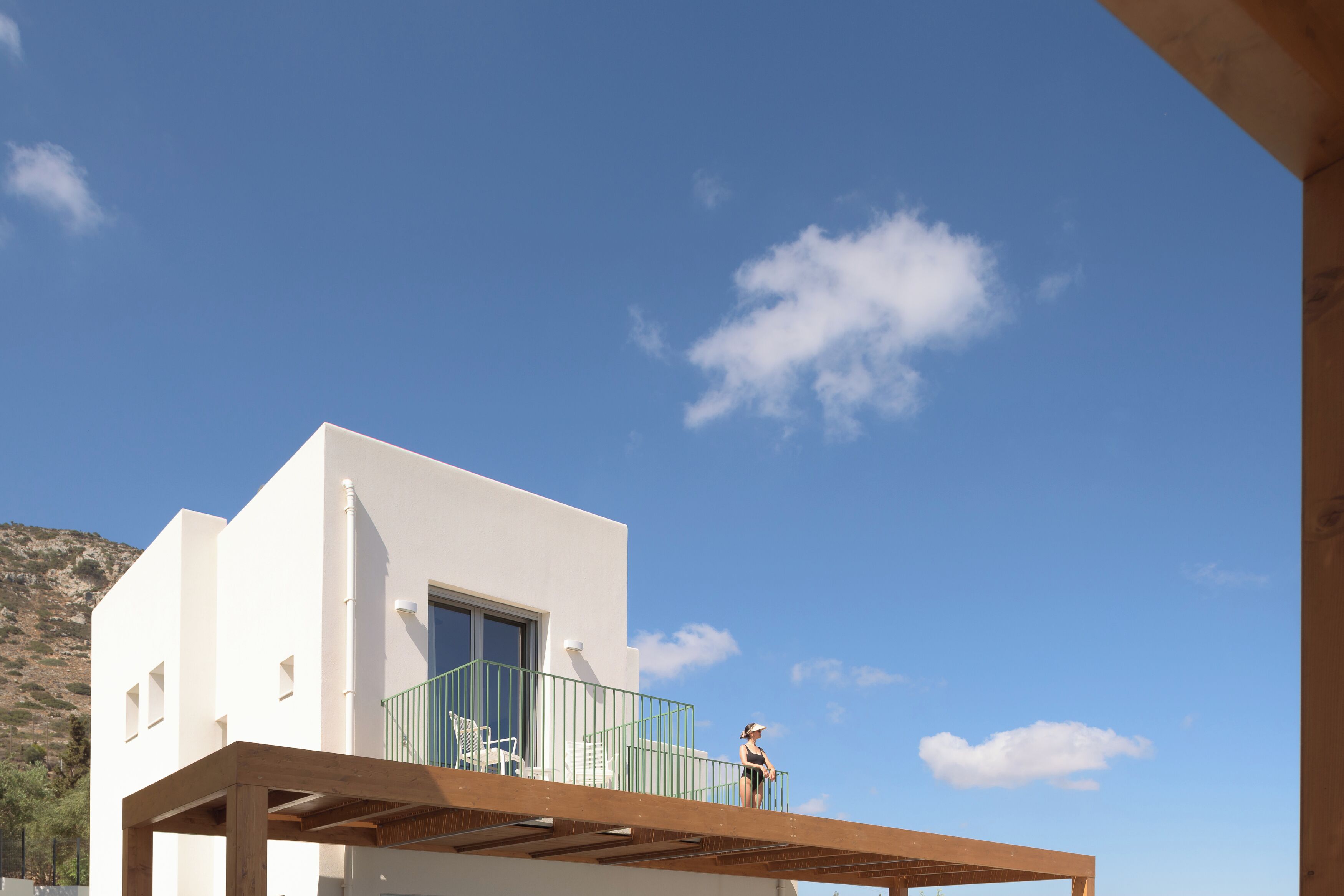 A modern building with a balcony, a clear sky, and a mountainous background.