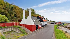 A narrow road flanked by traditional buildings with red and white facades, a stone wall, and a grassy area with trees. - "Malila" - 15m from the sea by Interhome (Hasle)