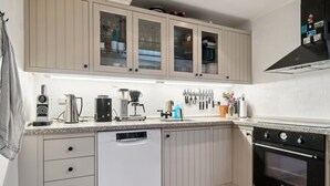 A modern kitchen with white cabinets, a dishwasher, a coffee maker, and an oven. - "Malila" - 15m from the sea by Interhome (Hasle)