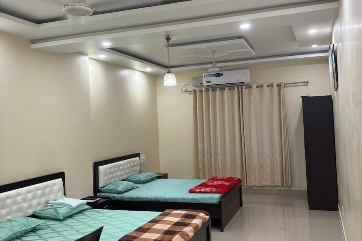 Una camera da letto moderna con due letti, una scrivania e un ventilatore a soffitto.