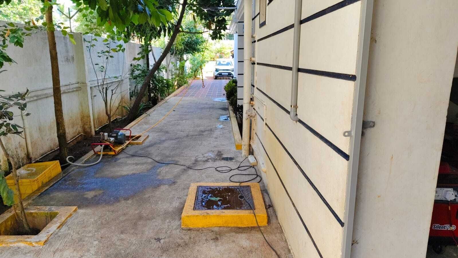 A narrow alleyway with construction equipment and materials, a parked car, and a building entrance.