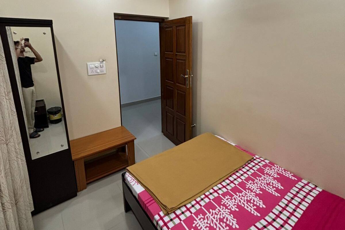 Una camera da letto con un letto, un armadio, uno specchio, una ventola a soffitto e una porta che dà su un'altra stanza.