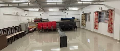 Ein geräumiger Saal mit Reihen blauer und roter Stühle, einem schwarzen Sofa und einem Empfangstresen.