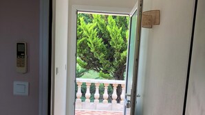 Ein Flur, der zu einer Glastür führt, von der aus man einen Balkon und Grünanlagen sieht.